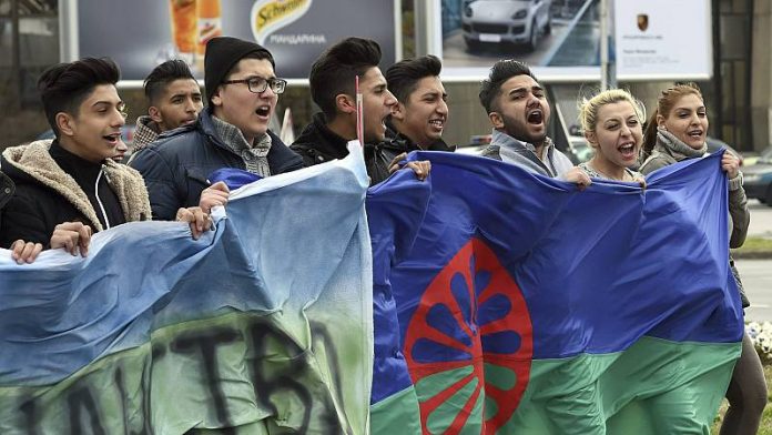 Grupo de jóvenes gitanos llevando la bandera del Pueblo Gitano en una manifestación / Georgi Licovski (EFE)